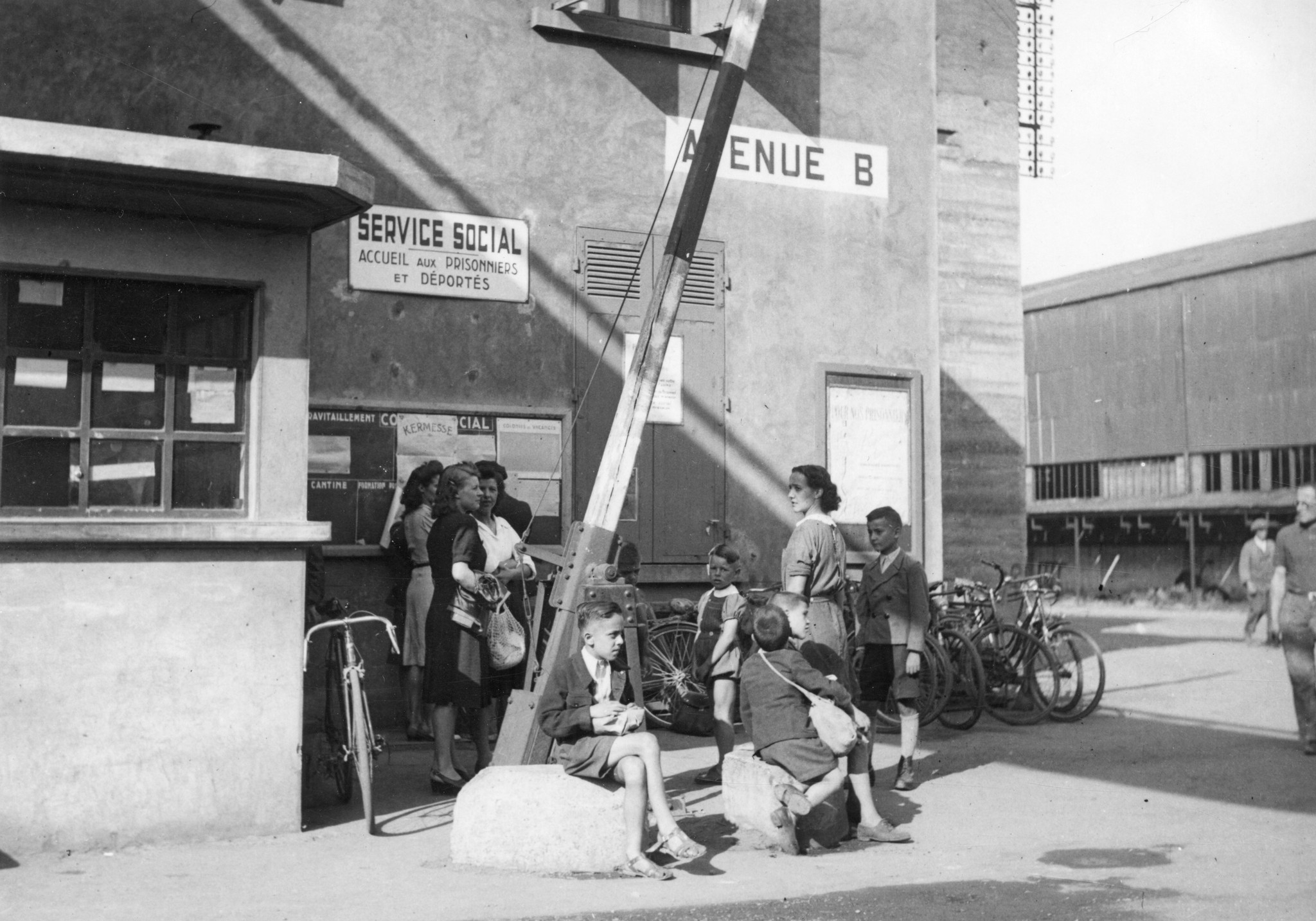 "Lyon 1945. Vor der Abfahrt der Buben in die Ferienkolonie Berliet." Frauen mit Kindern warten vor dem Sozialamt, vermutlich in den Berliet-Werke, Schild: "Service social. Acceuil aux prisonniers et déportés."