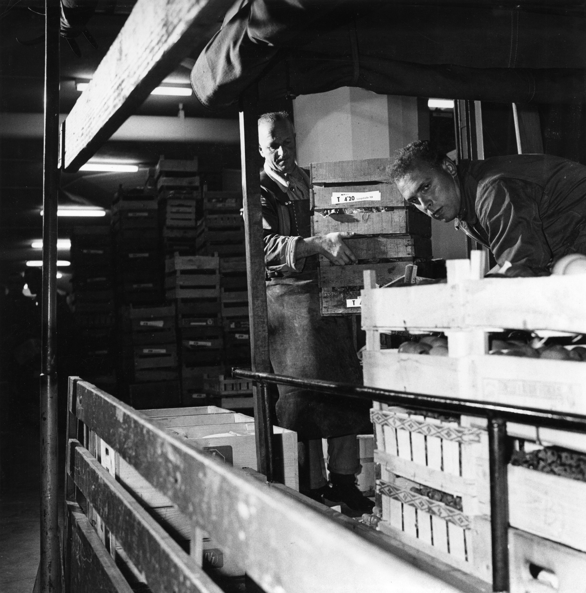 Männer beim Beladen oder Entladen von Gemüse / Früchten auf einem Lastwagen