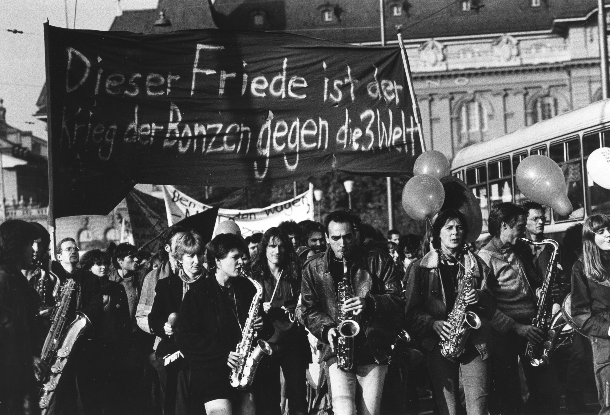Friedensdemonstration organisiert durch die SAH im November 1983; "Dieser Friede ist der Krieg der Bonzen gegen die 3. Welt"; musizierende Demonstranten im Vordergrund