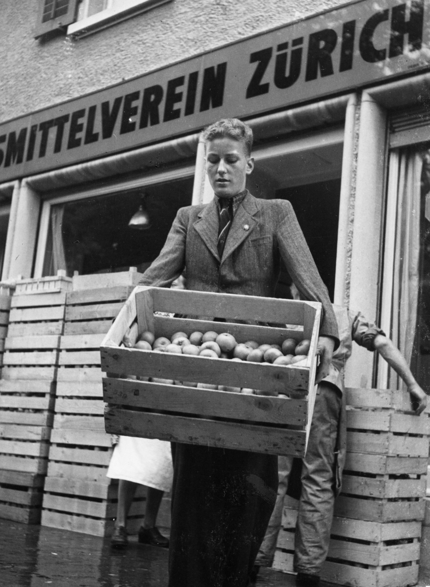 Mann trägt in Kisten verpackte Äpfel