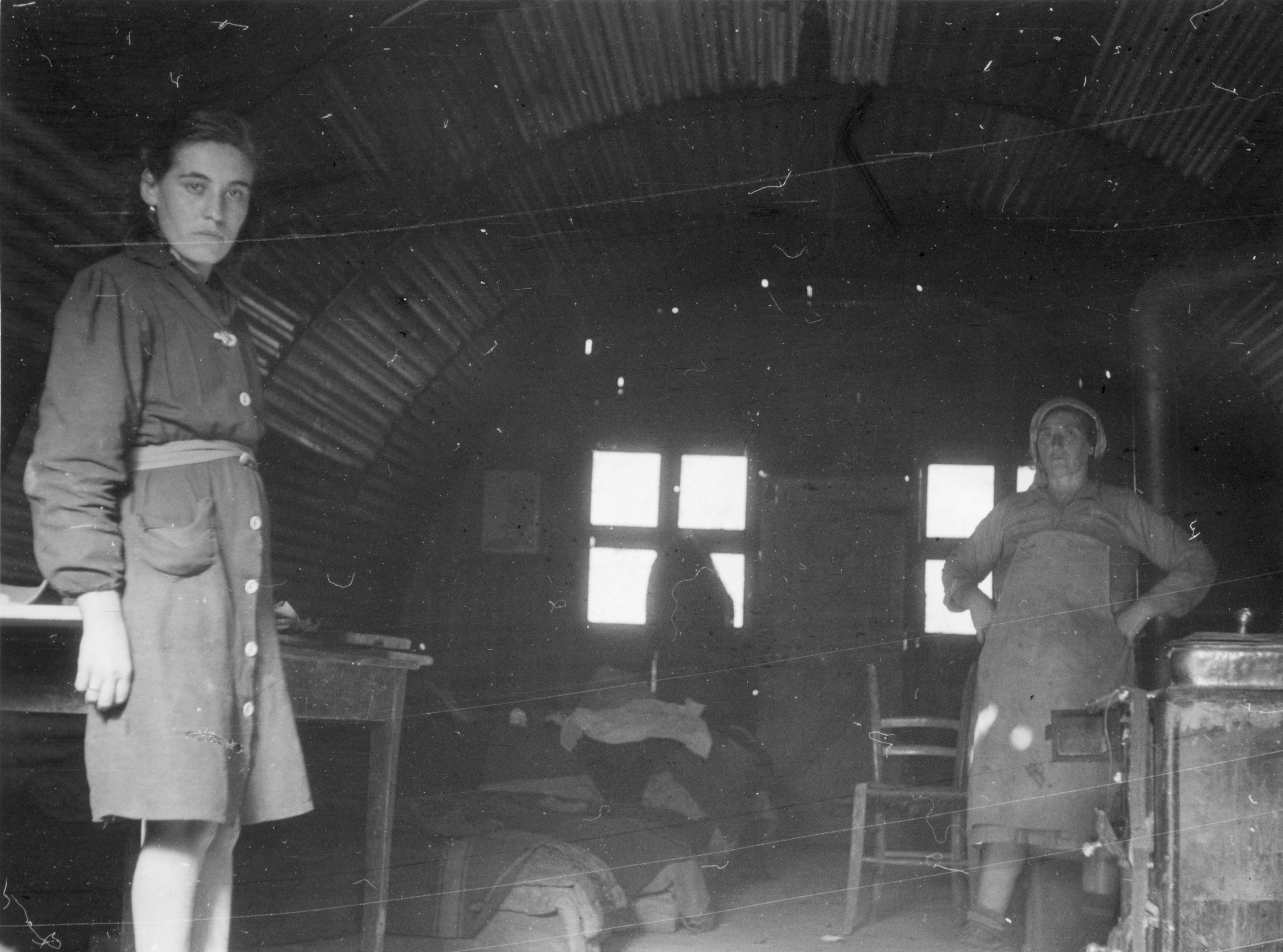 Pianoro, Januar 1946. Innensicht einer Baracke. Man sieht durch die Löcher in der Wand."; Menschen stehen in der Baracke
