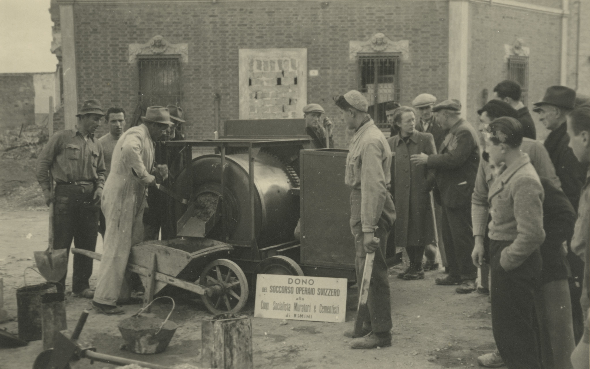 "Italien, März 1946. Cooperativa Muratori. Cementisti, Rimini"; Männer stehen um eine Maschine zur Zementherstellung und probieren sie aus