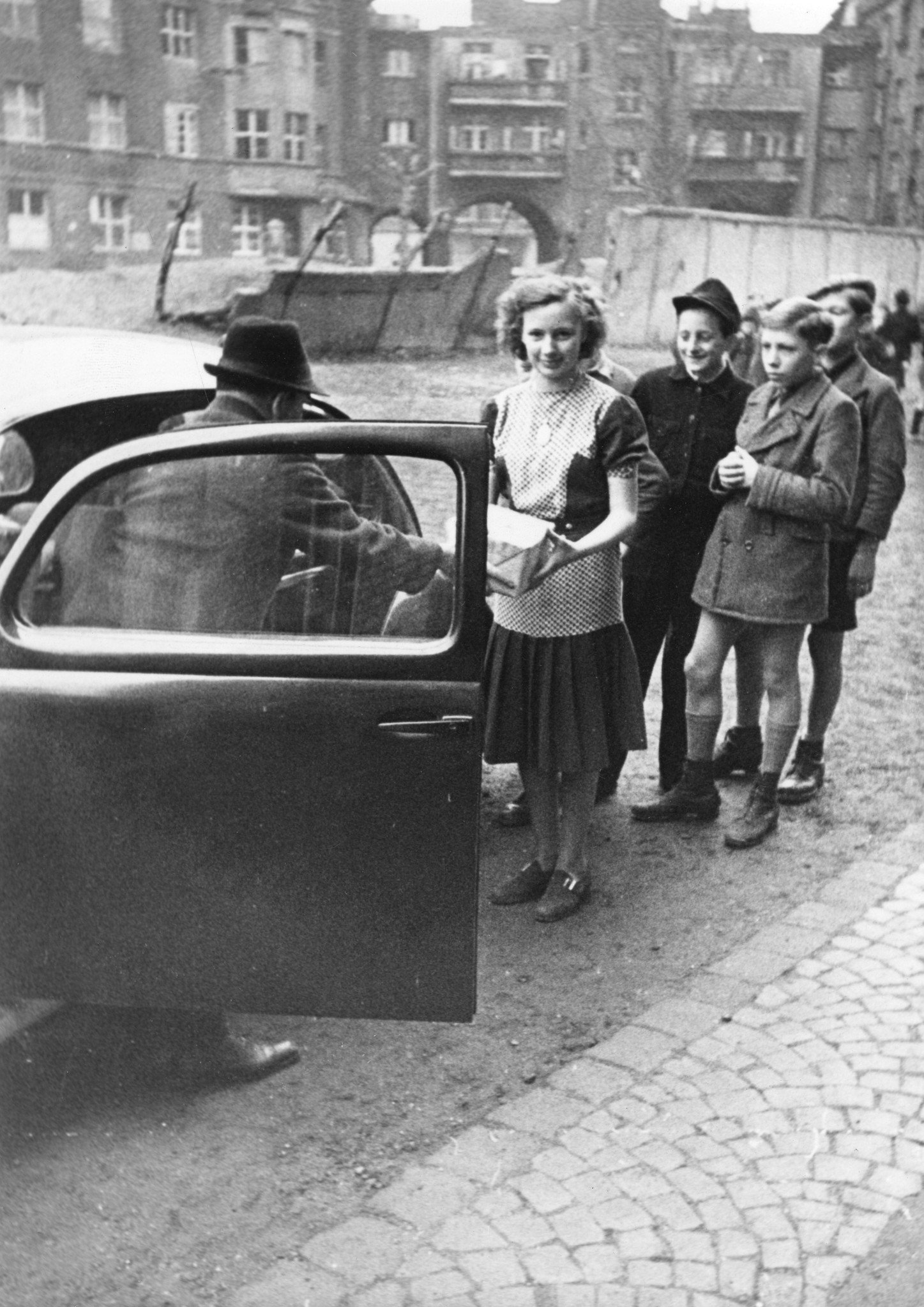"März 1948: Verteilung von Lebensmittelpaketen am die Schüler der Gemeinschaftsschule Düsseldorf"; Kinder nehmen aus einem Auto Pakete entgegen