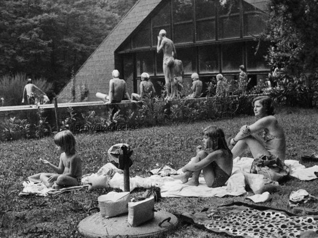 Bosco della Bella, Feriendorf für kinderreiche Familien - Mutter und Kinder sitzen auf der Liegewiese, hinten vergnügen sich Kinder und Erwachsene beim Schwimmbad; um 1975
