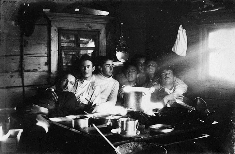 In der Reckholderhütte: Wandervögel sitzen am Tisch während einer Mahlzeit (Essnäpfe und Pfanne auf dem Tisch) (1920)