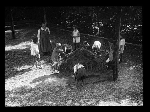 Diaserie zum Thema Kindergarten; Kinder mit Schaufeln und Beutreuerin um Erdhaufen stehend; um 1930