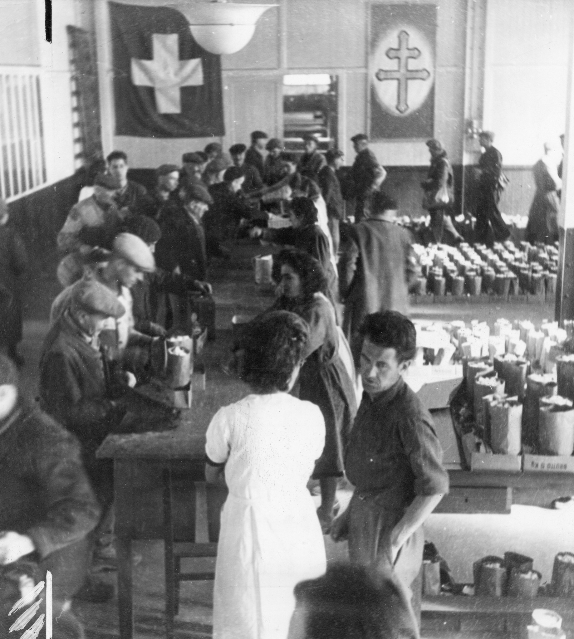 "Lyon, Oktober 1944. Die Verteilung beginnt Dienstag, den 3. Oktober 1944."  "Colis suisse', Jeder beschädigte Arbeiter erhält 2 kg. Zucker, 1 kg. Linsen, 1/2 kg. Teigwaren, 1 Büchse Tomatenpüree, 2 Büchsen Sardinen." Schweizer Fahne und Lothrin