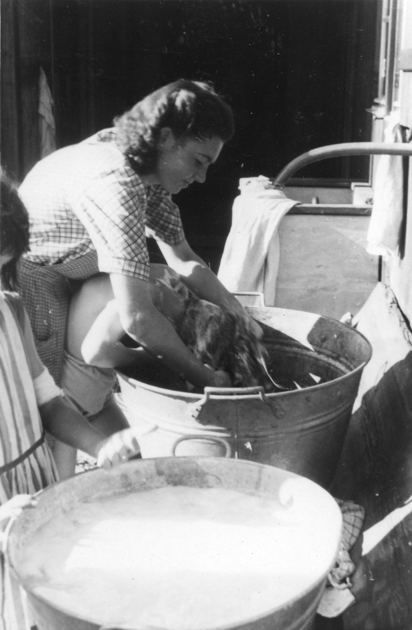 "Ferienkolonie für Ungarnkinder Kemleten / Kempttal Sommer 1947"; eine Betreuerin wäscht einem Mädchen die Haare