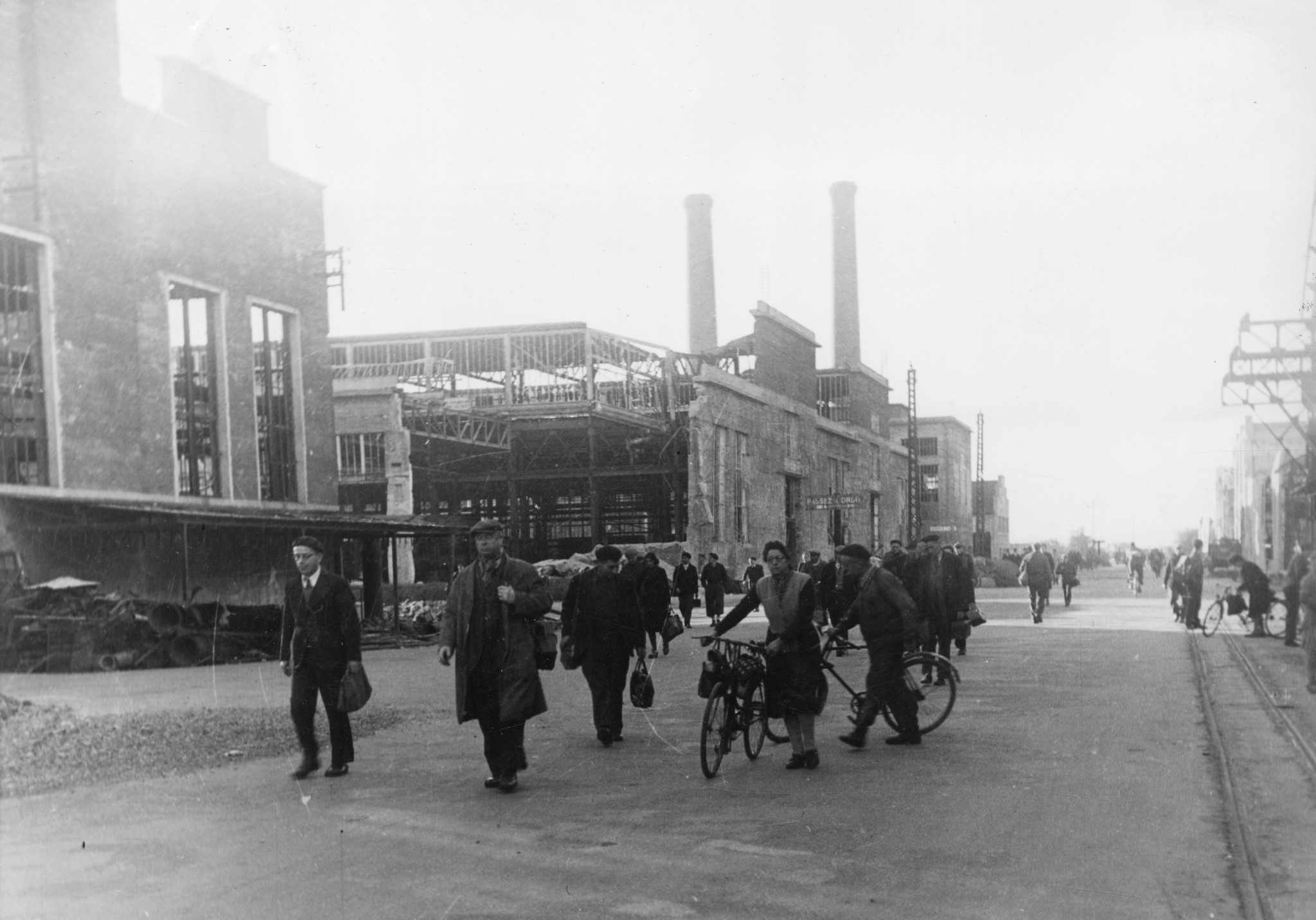 "Lyon, Usine(s) Berliet, 1944. In halbzerstörten, ungedeckten Fabriken beginnen die Arbeiter den Aufbau." Arbeiter und Arbeiterinnen auf dem Weg in den Berliet-Werke