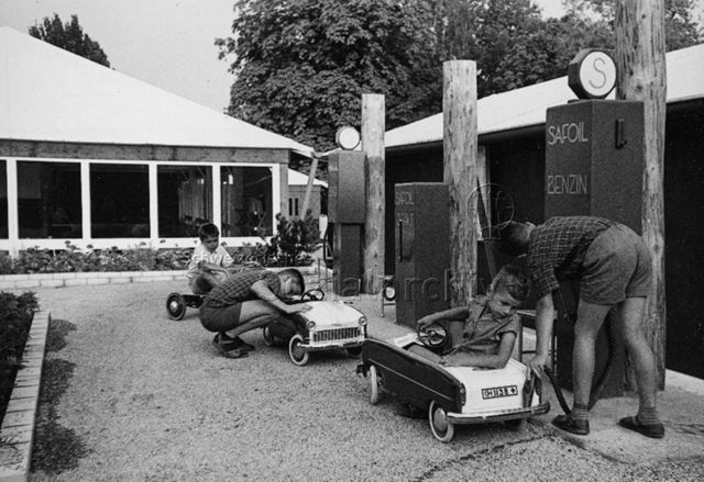 Jungen beim Spielen mit Tretautos an Spiel-Tankstelle; um 1965