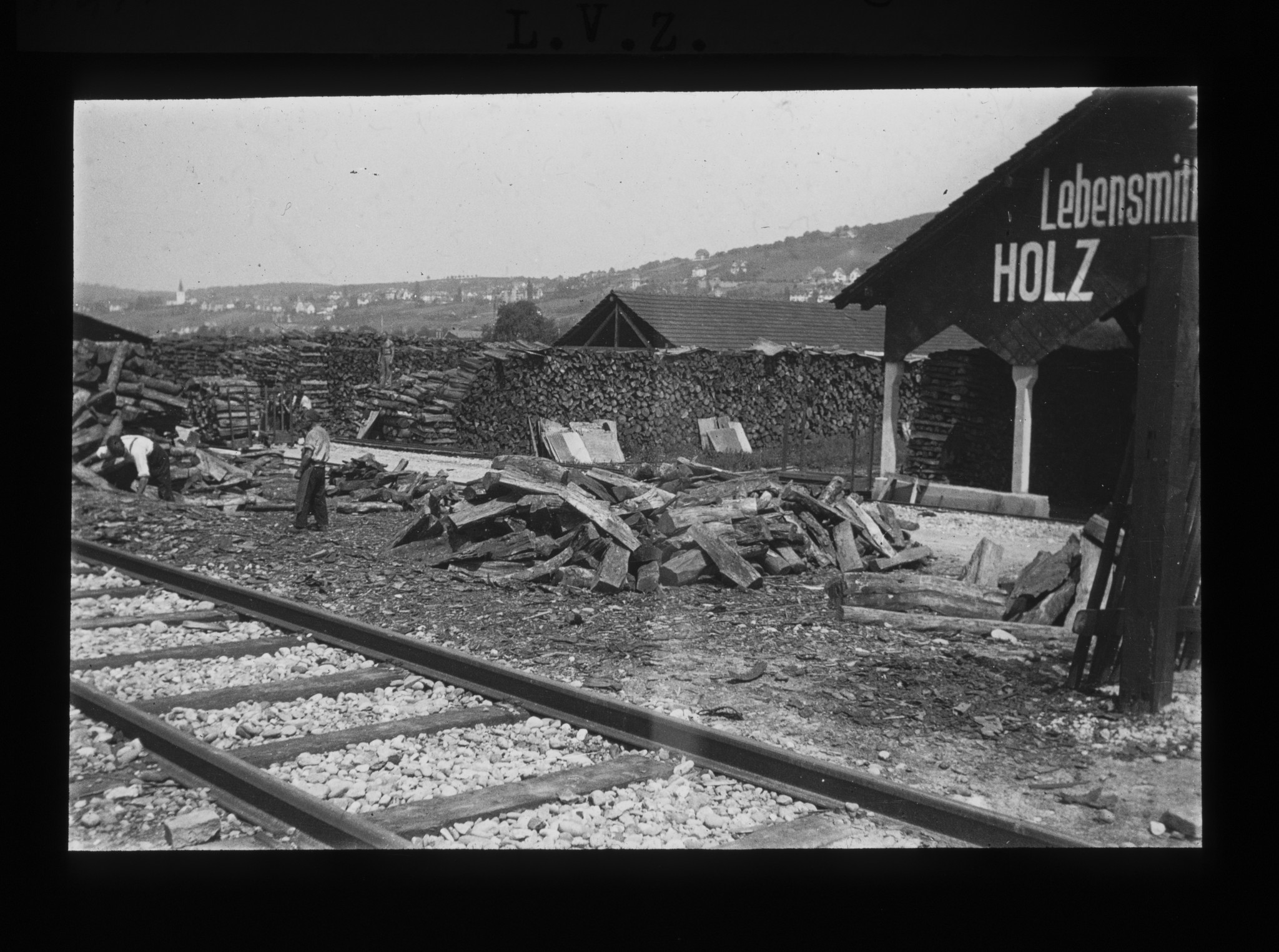 Dia: Brennmateriallager des LVZ an der Turbinenstrasse, Holzscheite und davor Schienen.