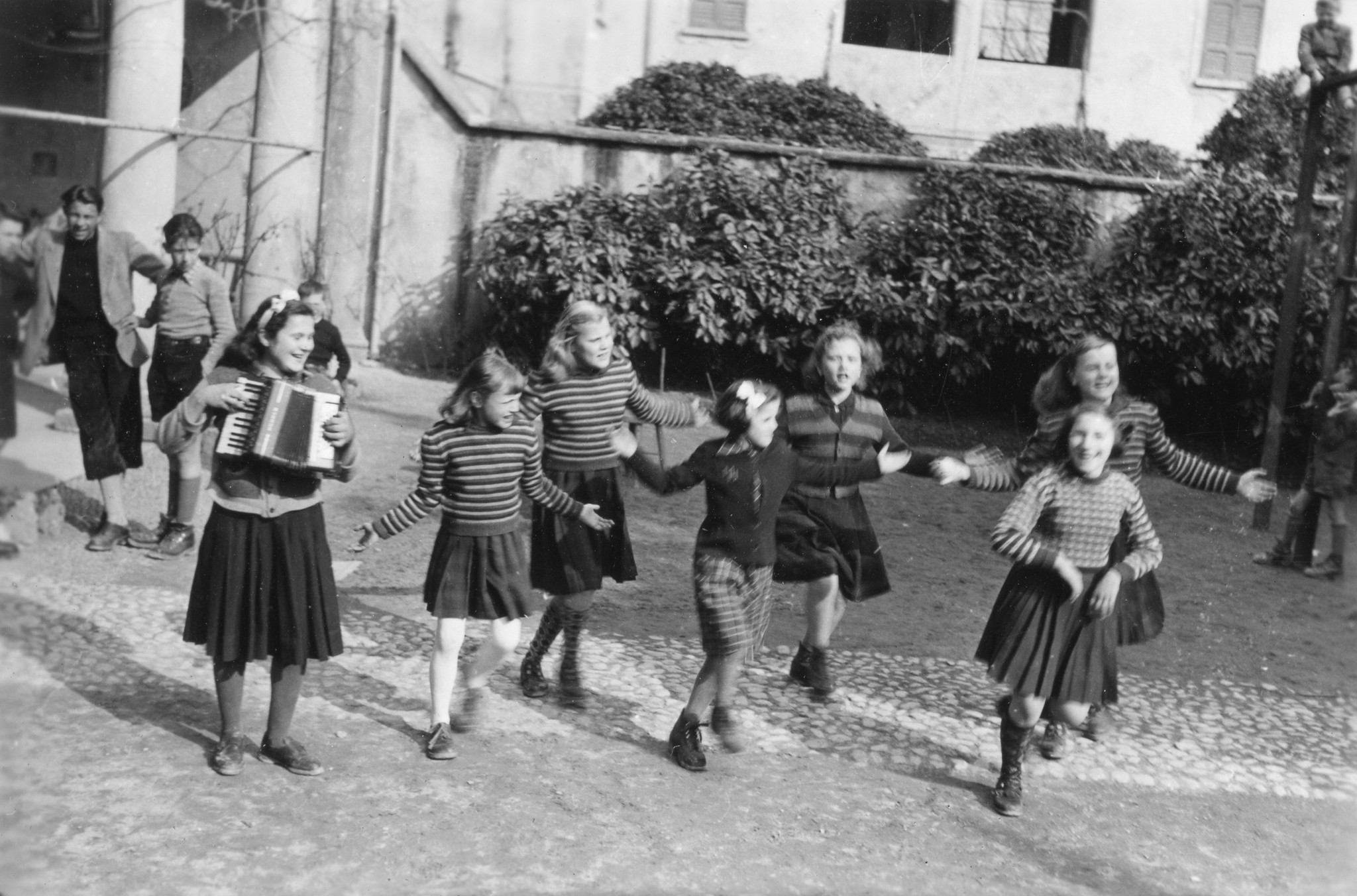 Tschechische Kinder in Brusata, Dezember 1951 bis März 1952; eine Gruppe von Mädchen tanzend und singend, vermutlich im Garten eines Kinderheimes