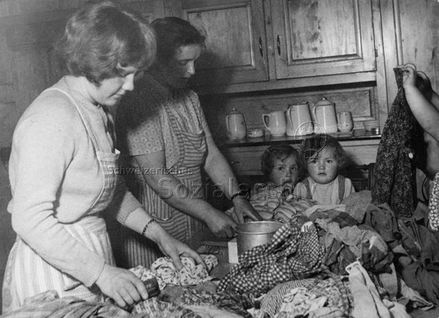 Praktikantinnenhilfe - Praktikantin und Mutter beim Wäschewaschen, zwei Kinder sitzen mit am Tisch; um 1965