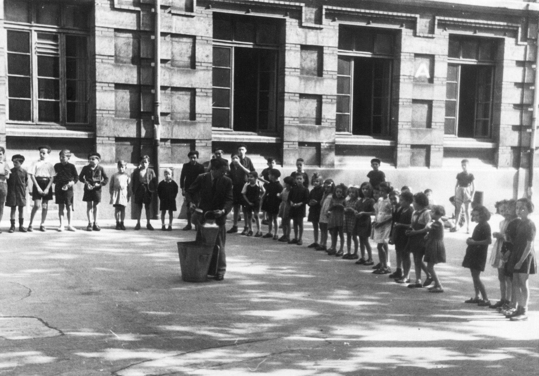 "Saint-Etienne, 1945.Verteilung der Don Suisse Milch in den Primarschulen. Deficiente Schüler bekamen während cca 3 Monaten täglich einen 1/4 L. Milch. Die Milch wurde entweder in den Schulkantinen oder von den Lehrern selbst [...] präpariert. [