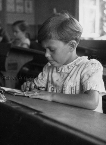 Mädchen sitzt an Schulbank und lernt; um 1970