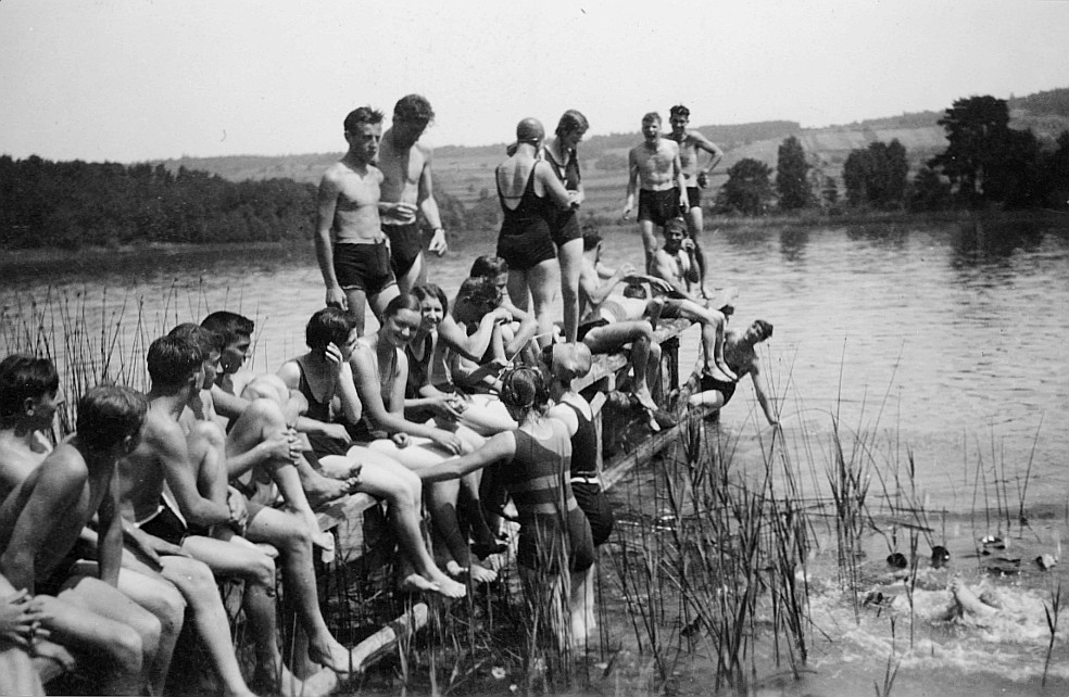 Wandervögel der Ortsgruppe Kreuzlingen in Badeanzug sitzen auf der Landungsbrücke bei einem See (1930)