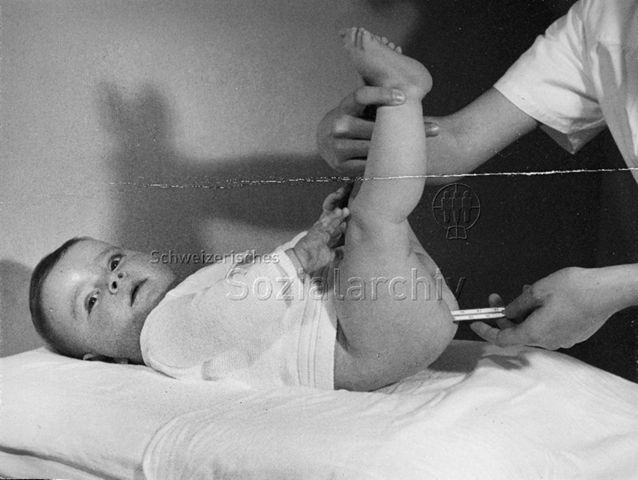 Frau misst die Körpertemperatur eines Säuglings; um 1965