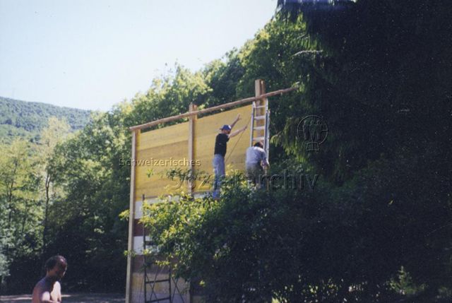 Bosco della Bella, Feriendorf für kinderreiche Familien - Männer stehen auf Leiter und Gerüst und bauen Wand aus Holzbrettern; 2000