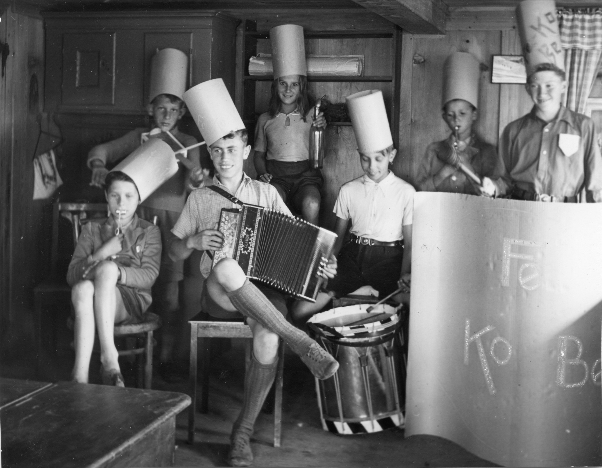 Kinder machen im Wohnzimmer des Hauses Musik und tragen Papierhüte