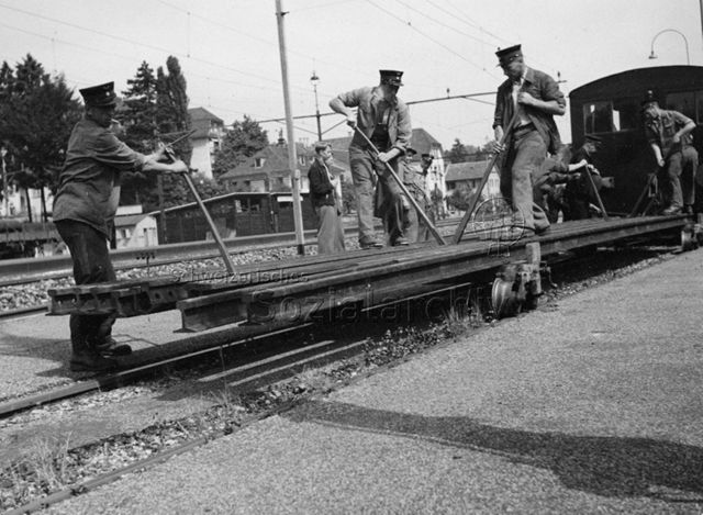 "Park im Grüene", Rüschlikon, Transport eines alten Zugwaggons - Männer beim Abladen von Zugschienen; um 1960