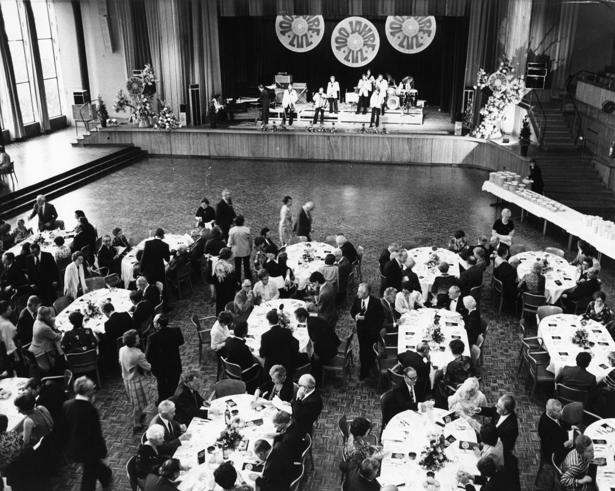 Jubiläum 100 Jahre Lebensmittelverein Zürich 1978: Besucher an Esstischen, Servicepersonal und Band auf Bühne