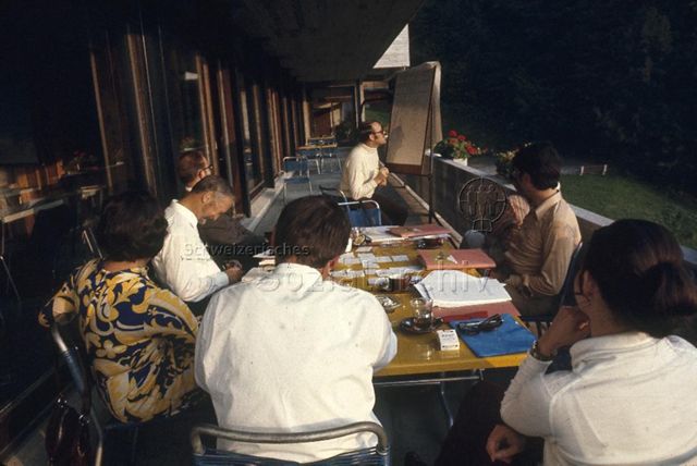 "SVEB-Kurs, Morschach" - Teilnehmende sitzen draussen am Tisch, ein Mann sitzt am Flipchart; 1971