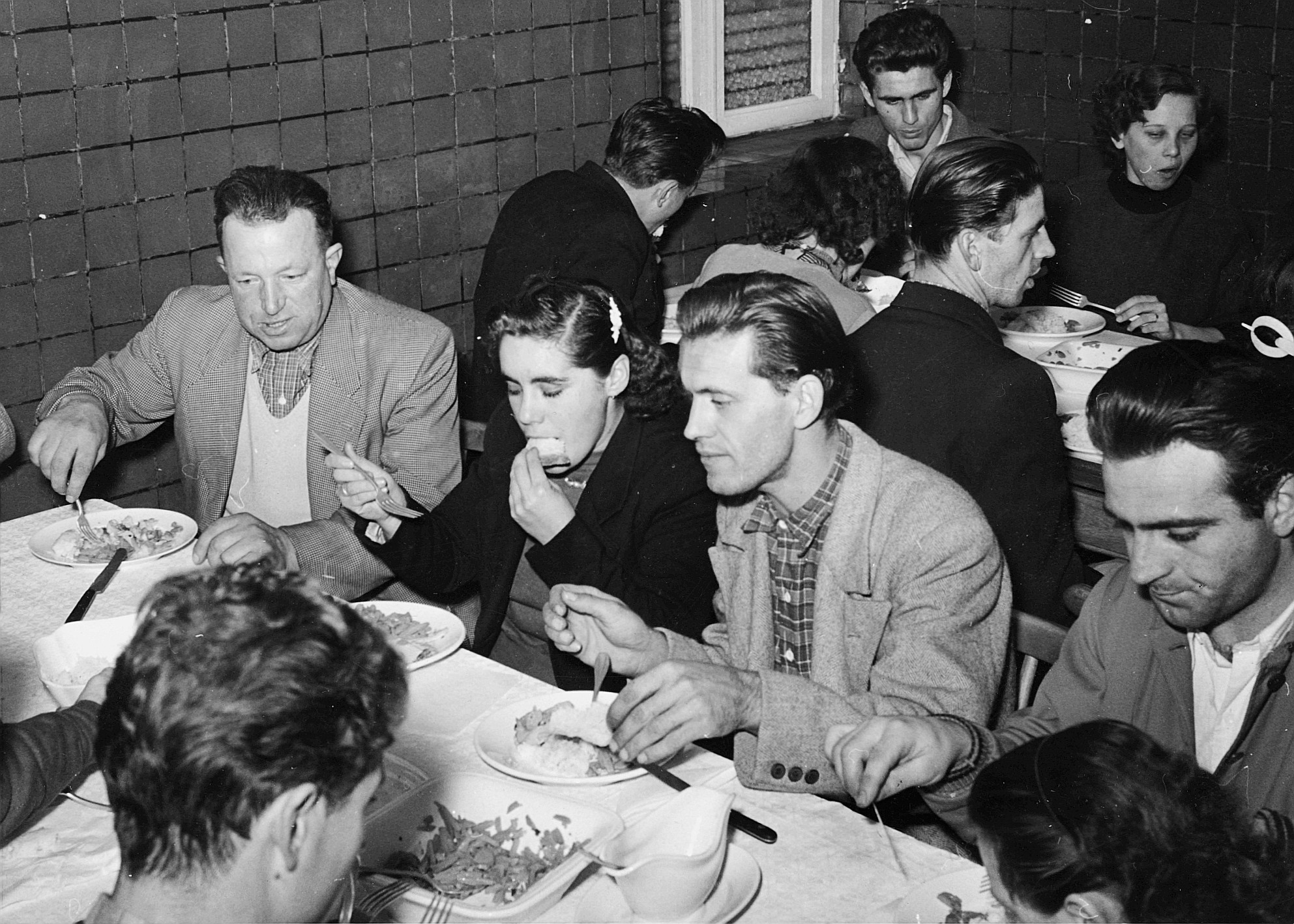 Am Tisch vereint, vergessen sie ihr Elend (Entraide Ouvrière Luxembourgeoise); Menschen am Tisch sitzend und essend