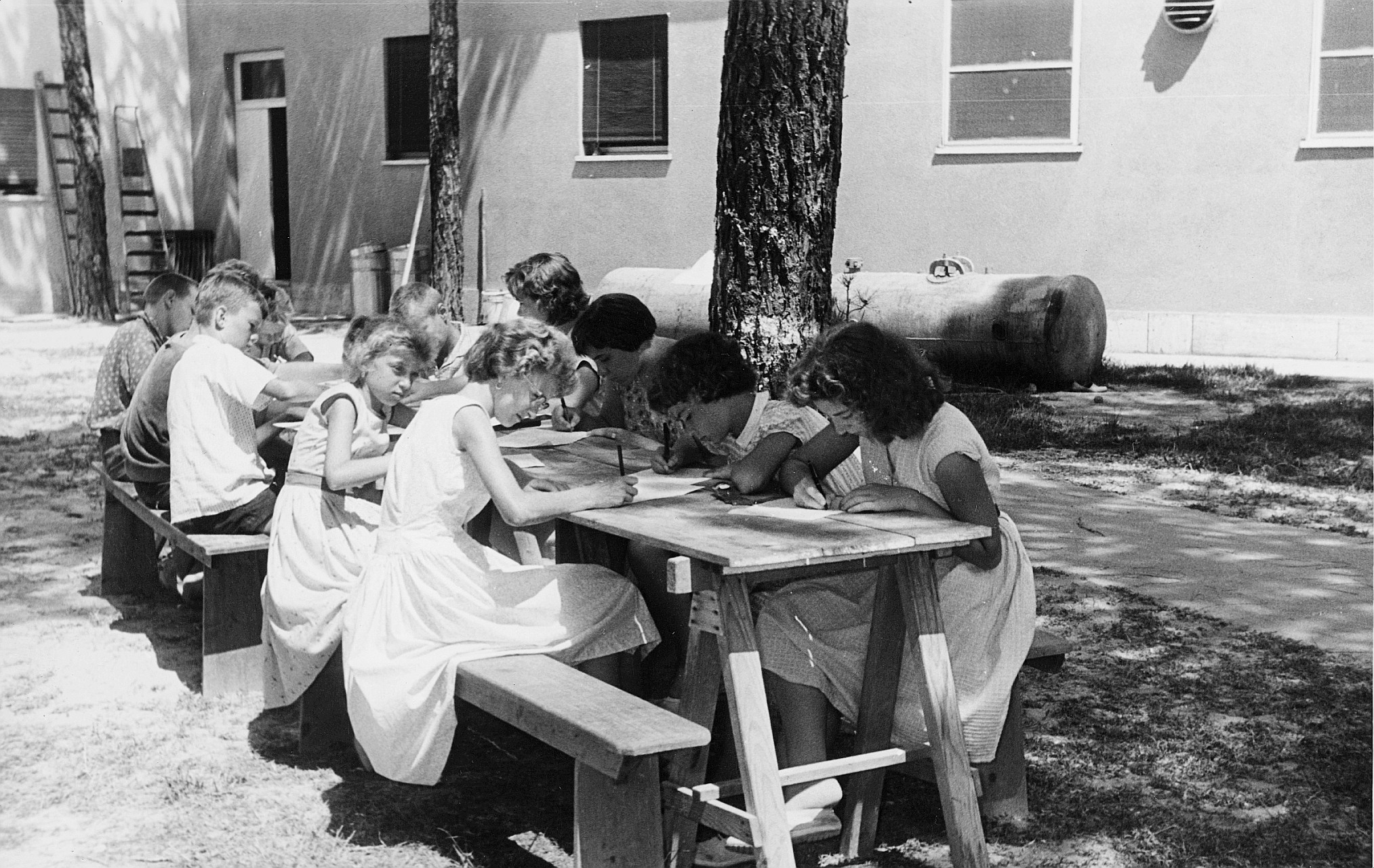 Kinderheim für Flüchtlinge; Kinder an einem langen Tisch sitzend und schreibend