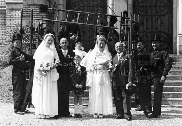 Doppelhochzeit Kaminfeger - zwei Ehepaare, flankiert von Kaminfegern