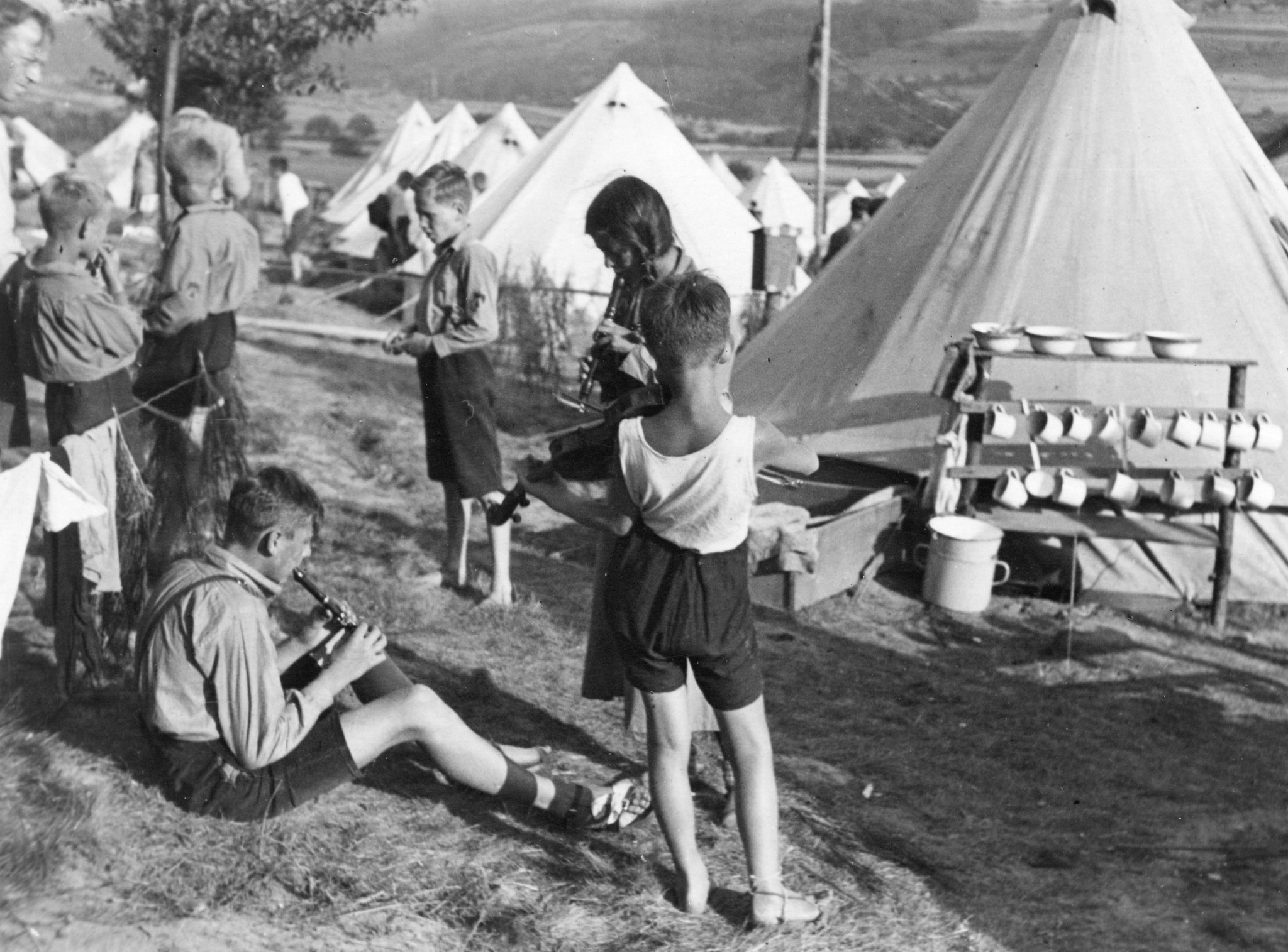 "Die Polen beim Musizieren"; Kinder im Lager der Roten Falken hören den Männern zu, die musizieren