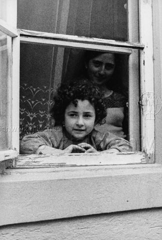 "Neustadtgasse, Winterthur, Beilage 'Kind und Eltern'" - Mädchen und junge Frau blicken aus dem Fenster in die Kamera; um 1970