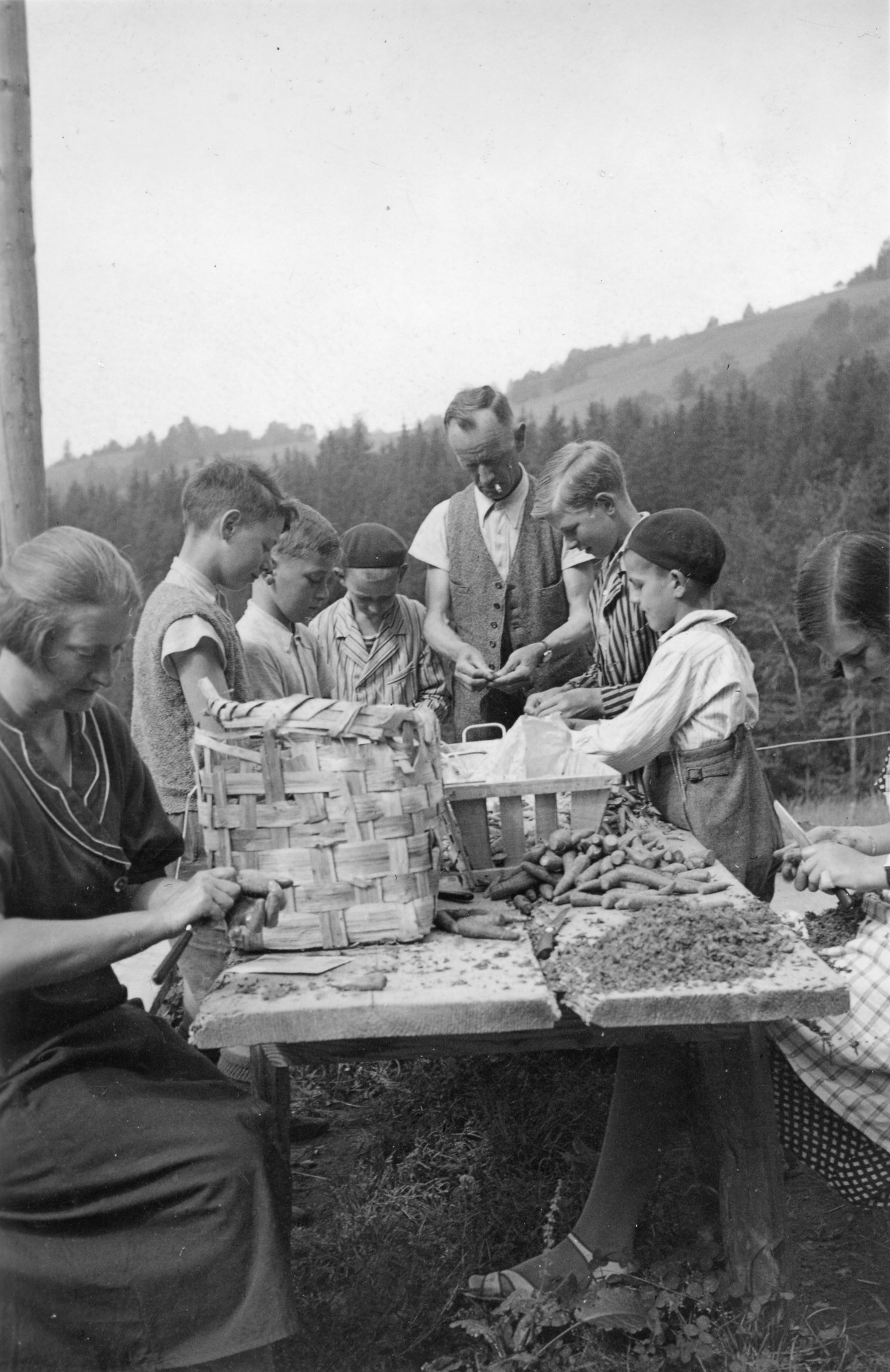 Kinder und Betreuer sitzen draussen und schälen Möhren