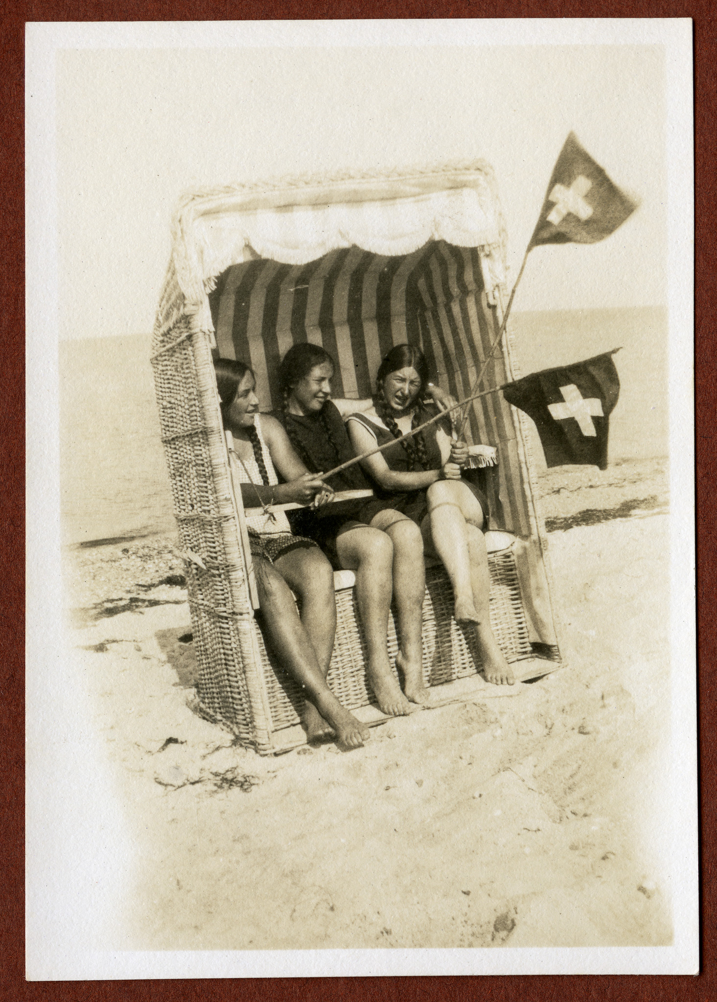 Sommerfahrt nach Deutschland: Drei Wandervögel (Mädchen) sitzen in einem Strandkorb am Nordseestrand (vermutlich); zwei Wandervögel