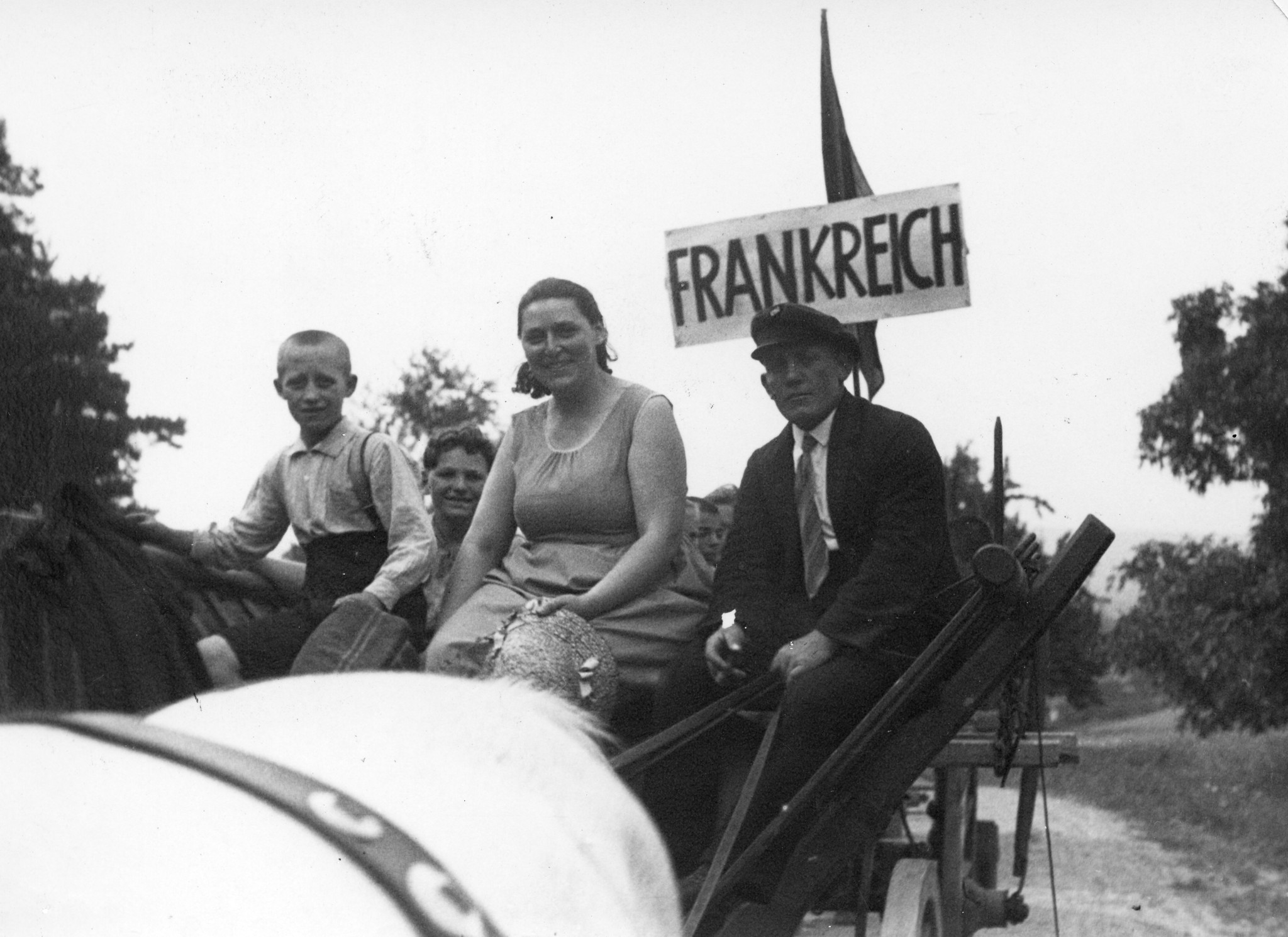 "Genossin Grimbach, Gemahlin des franz. sozialist. Abgeordneten, auf der Fahrt nach Westburg"; Kutscher, Frau und zwei Knaben sitzen auf der Kutsche mit der Beschriftung "Frankreich"