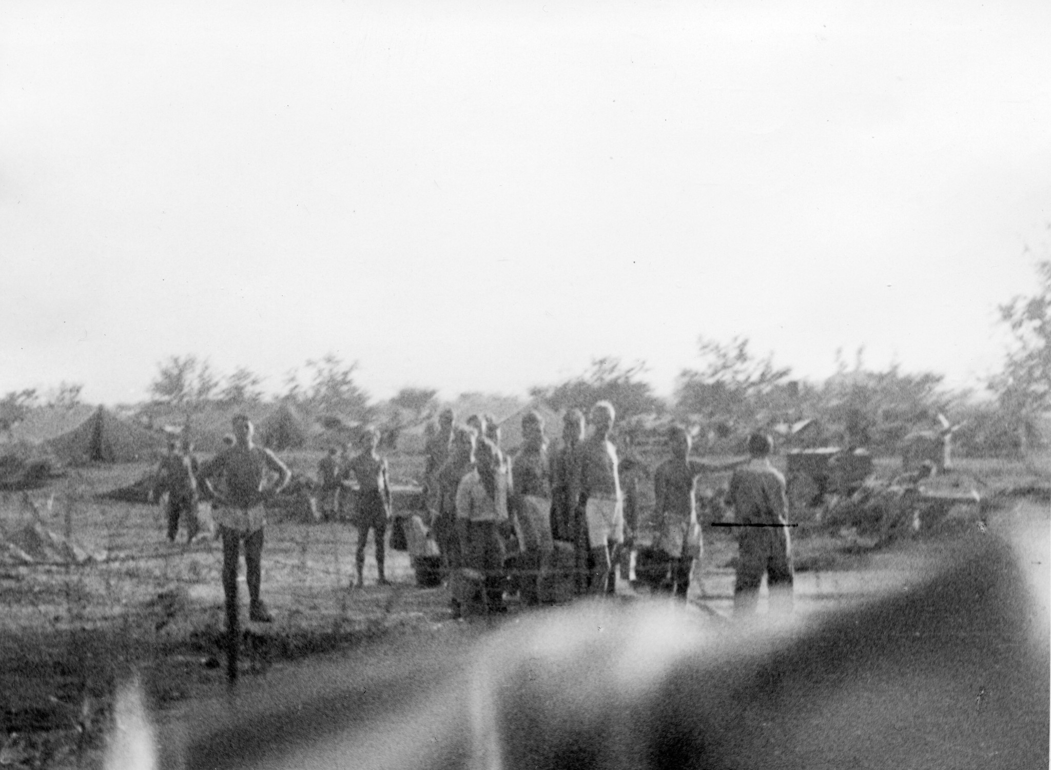 "Zwischen Ravenna und Rimini, 1945. Ein deutsches Gefangenenlager mit 80000 Insassen. (Photografieren verboten!)"; Gefangene hinter einem Zaun