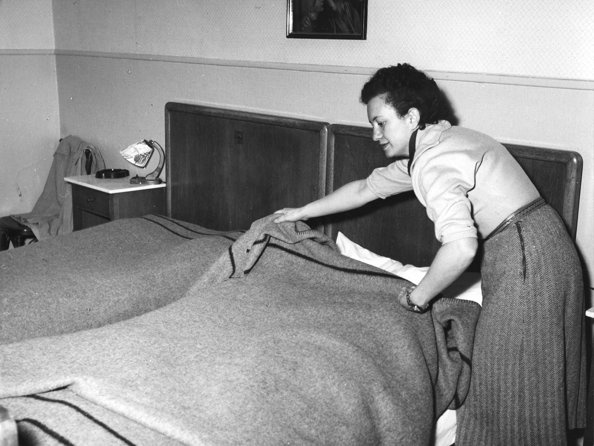 Eine Frau legt eine Decke auf ein Bett