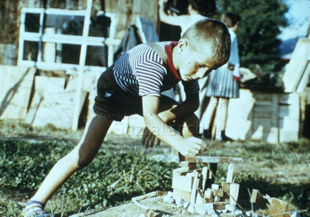 "Mini-Robinsonspielplatz" - Junge beim Basteln eines Spielplatzmodells; um 1970