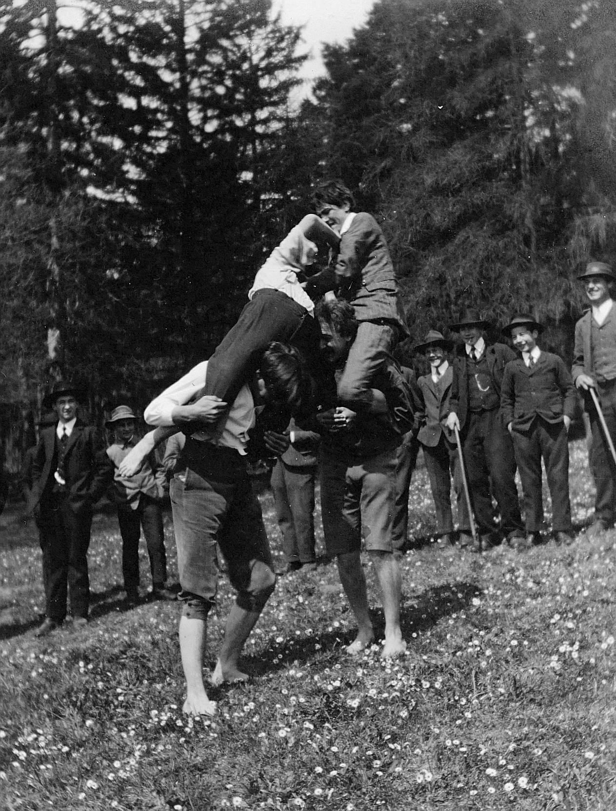 Wandervögel spielen im Freien: Zwei Wandervögel tragen auf den eigenen Schultern zwei andere Wandervögel, welche einen Kampf zwische