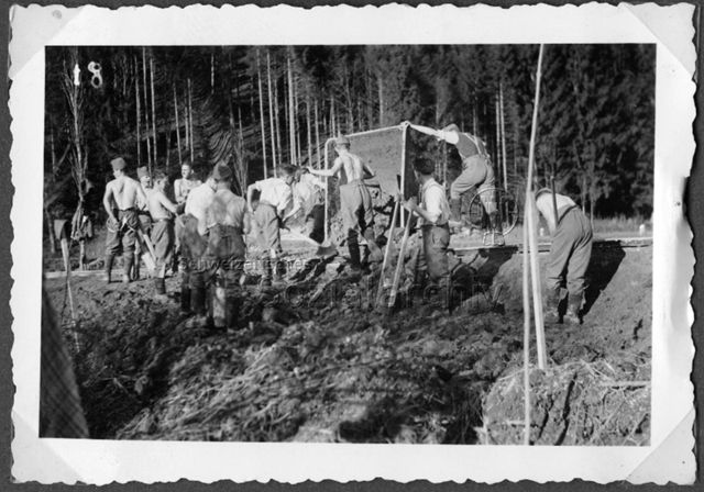 Album Alfred Brauchli, Teil 1/3: 699 Tage Aktivdienst 1939-1945 als Sanitätssoldat bei der Sanitätskompanie I/​7, Thurgau:- Baustelle der Armee mit zwei Soldaten an gekippter Kipplore, einer leert sie mit Pickel, andere graben mit spatenähnlichen Geräten mit zwei Stielen