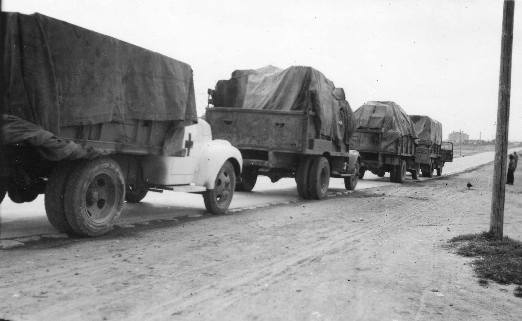 Schulmaterialtransport: mehrere bedeckte Lastwagen fahren hintereinander (Rotes Kreuz?)