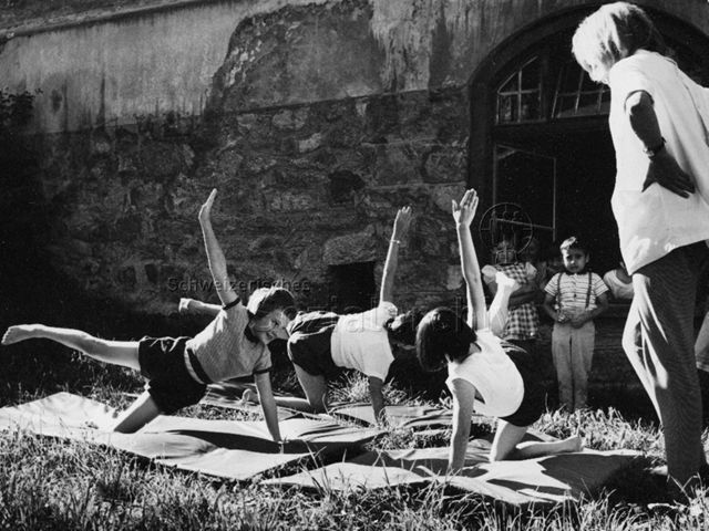 "Kinderheilstätte, Davos, Gymnastik" - Drei Kinder bei Gymnastikübungen im Freien; 1971