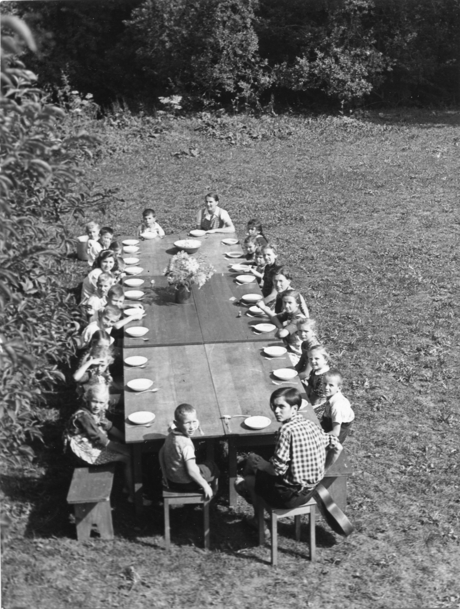 Kinder essen draussen mit Betreuern an einem Tisch