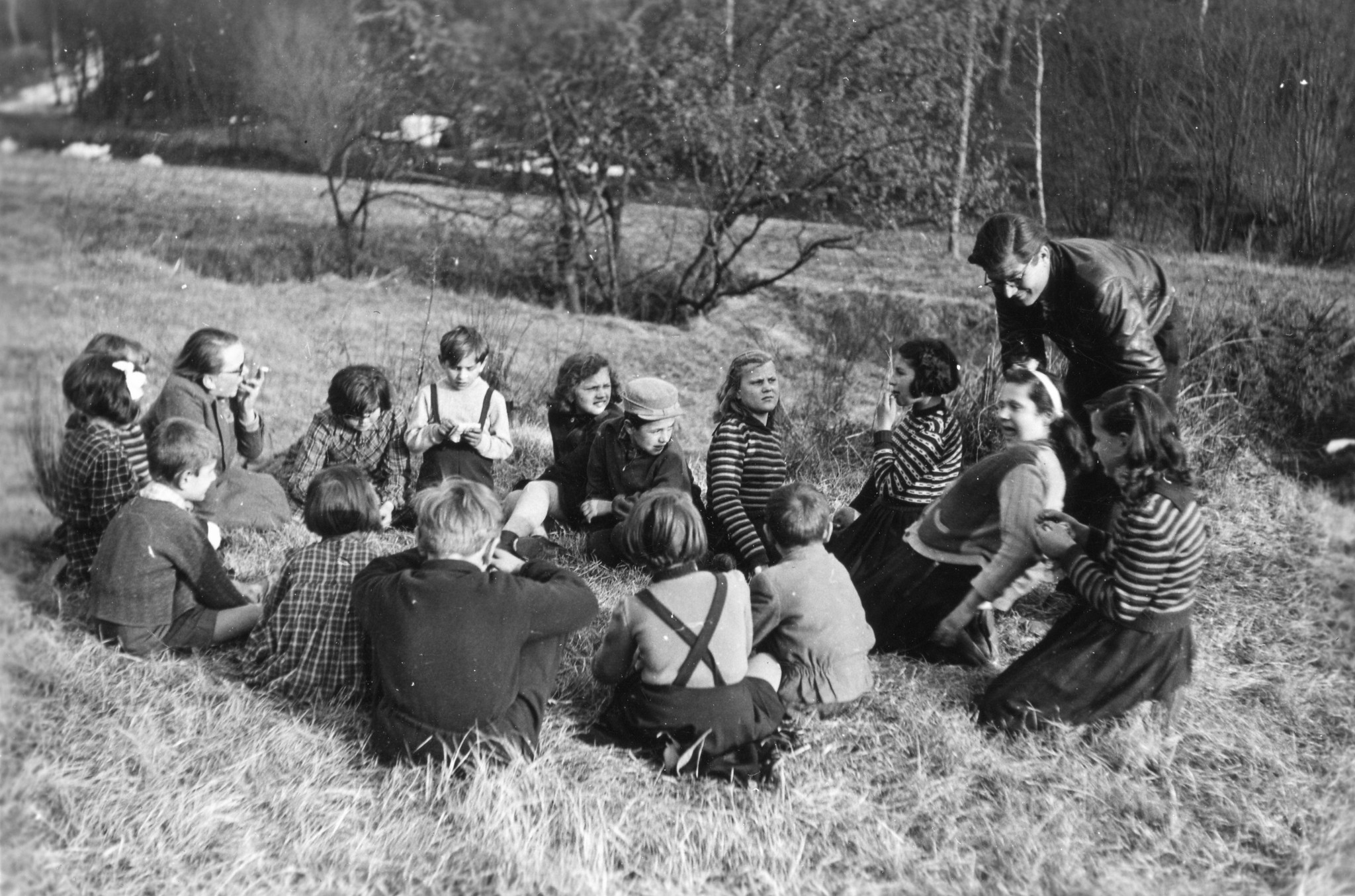 Tschechische Kinder in Brusata, Dezember 1951 bis März 1952; eine Gruppe von Kindern und einem Erwachsenen in einer Wiese sitzend