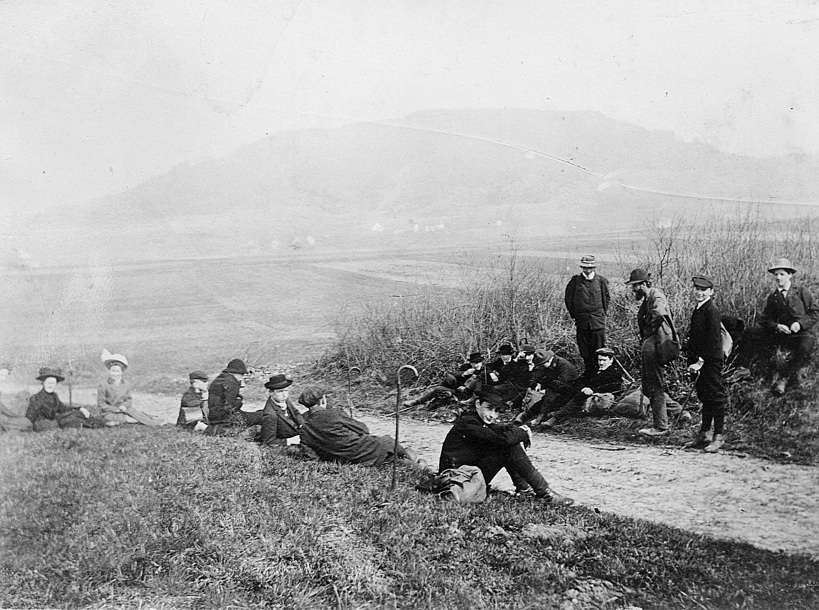 Wandervögel sitzen auf der Wiese, am Rand eines Schotterwegs (1910)
