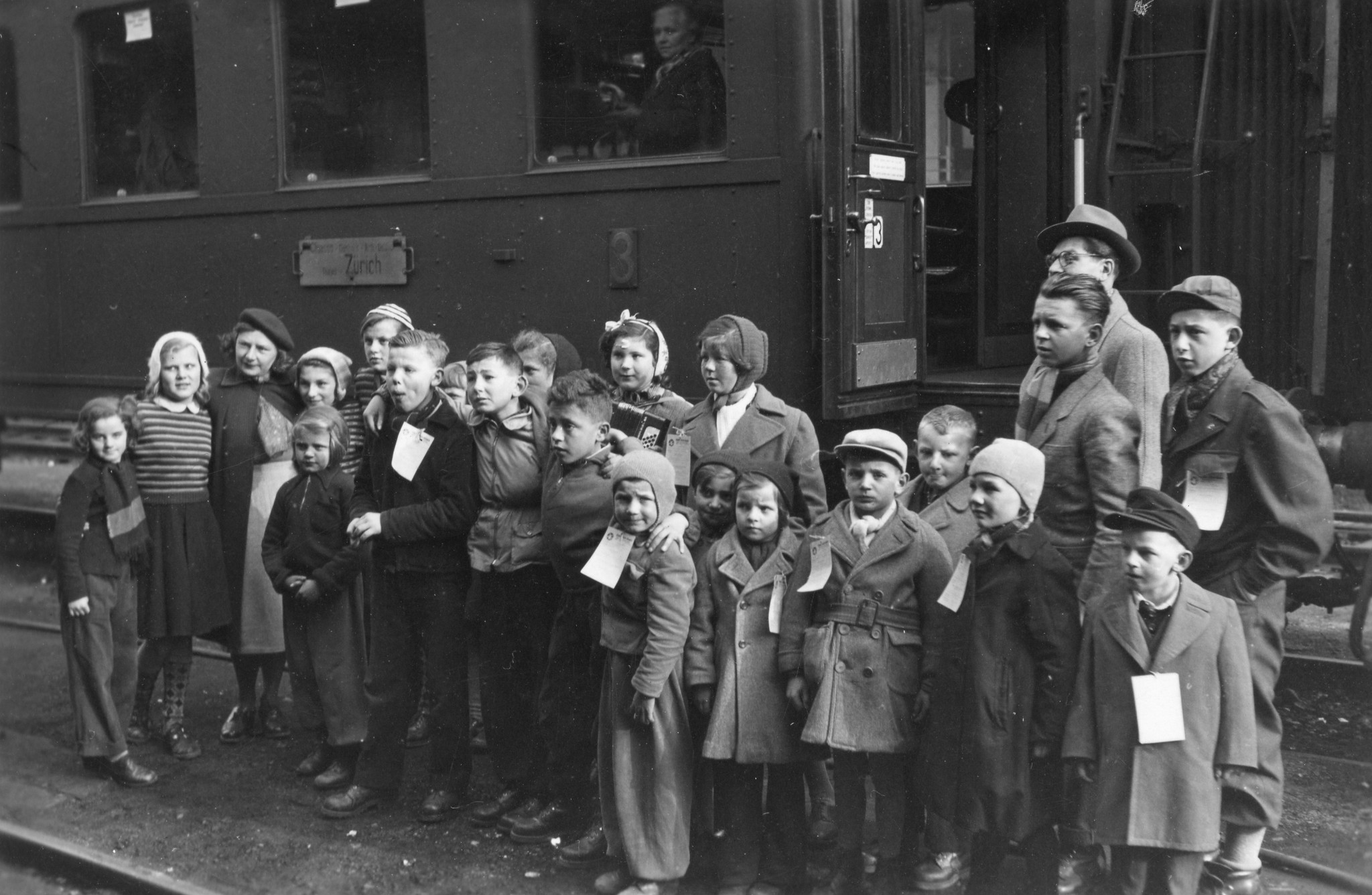 Tschechische Kinder in Brusata, Dezember 1951 bis März 1952; eine Gruppe von Kindern, vermutlich auf der Heimfahrt, posiert vor einem Zug Richtung Zürich