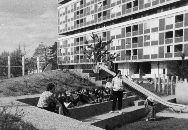 Kindergarten "Pamplemousse", Lignon, Genf - Kinder sitzen mit Aufseherin auf Steintreppe; um 1980