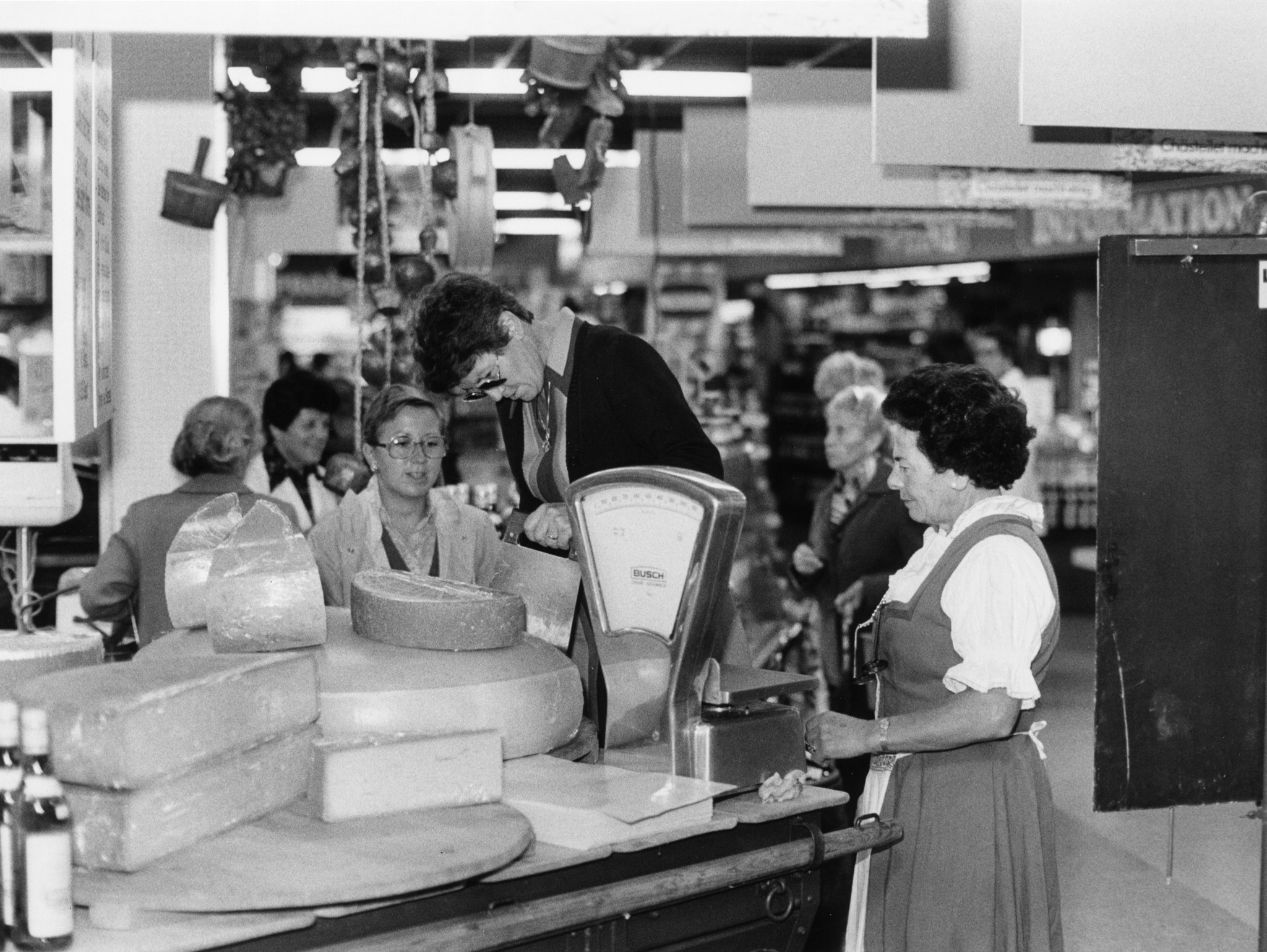 Werbeaktion in einem Laden des Lebensmittelvereins Zürich: Käse-Abstechen und Schätzen des Gewichts, Angestellte und Kundinnen