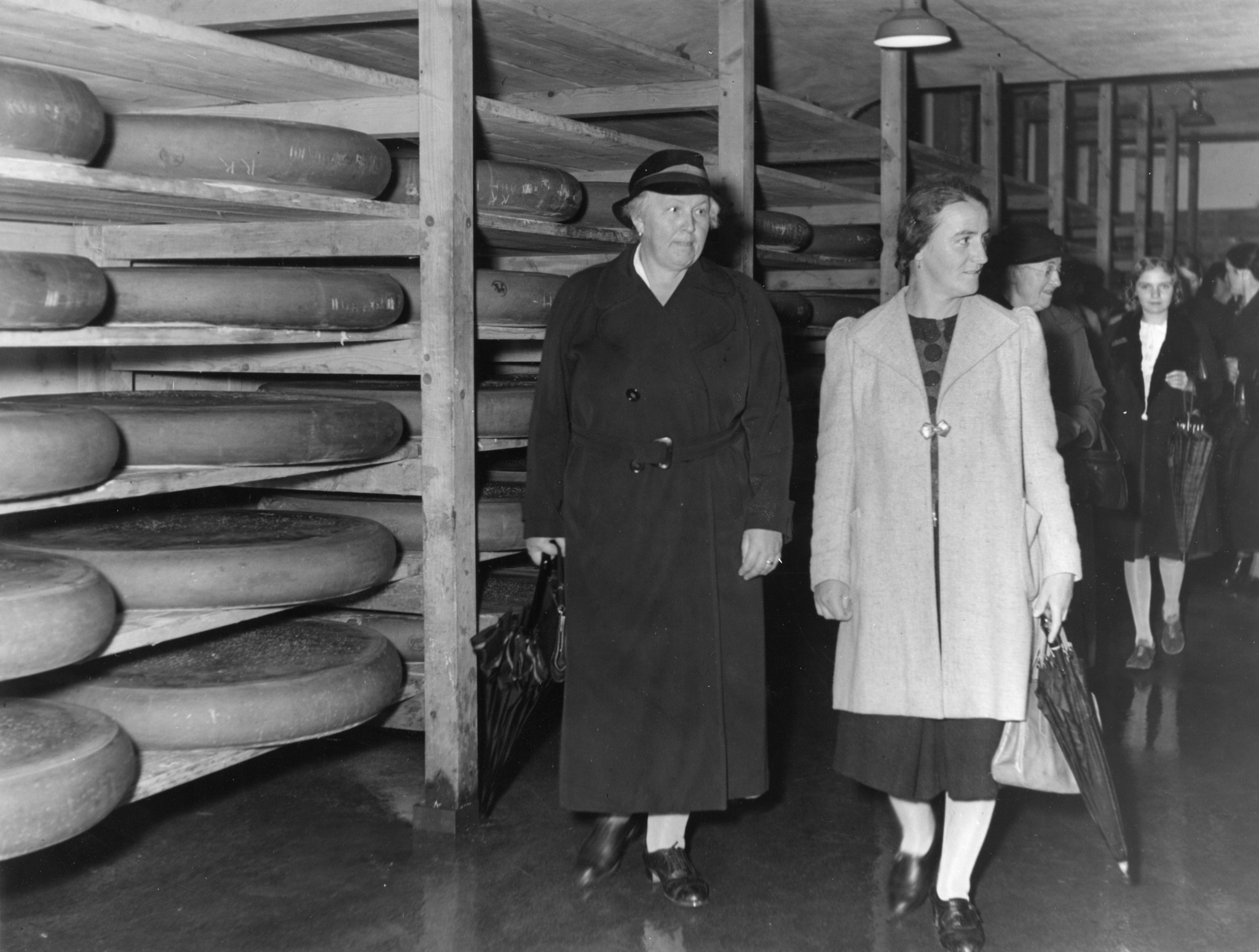 Frauen auf Betriebsbesichtigung in einem Lagerraum für Käse des Lebensmittelvereins Zürich