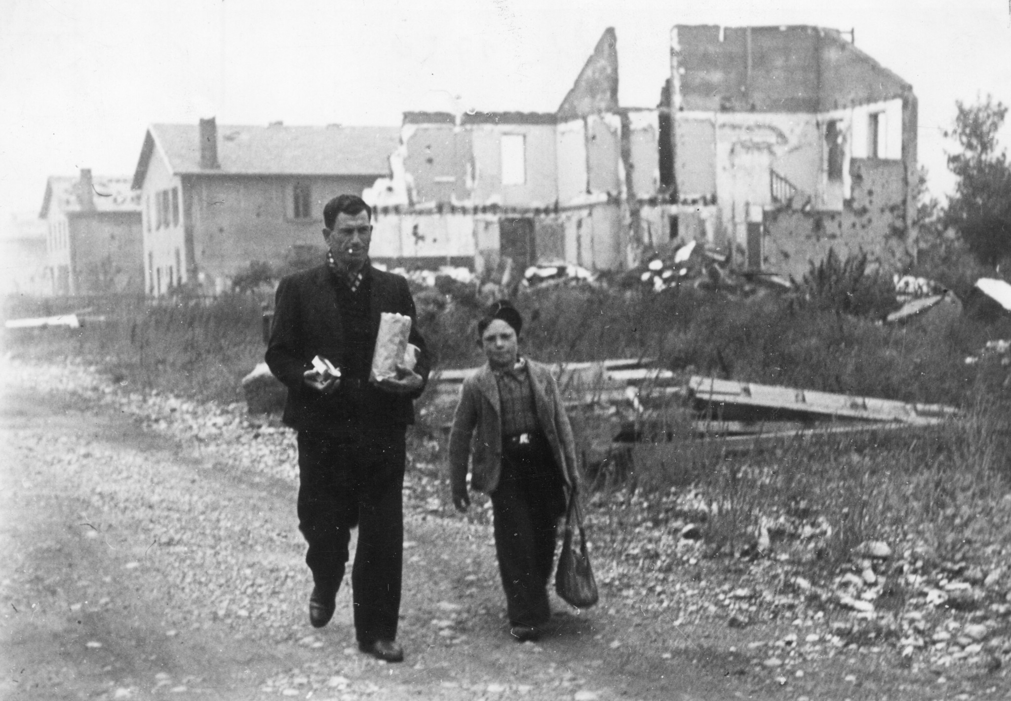 "Lyon, Oktober 1944. Auf der Strasse im Arbeiterviertel der Stadt, das durch ein Bombardement zerstört wurde." Vater und Sohn (?) kommen aus der Lebensmittelverteilung des SAH in den Berliet-Werke zurück.