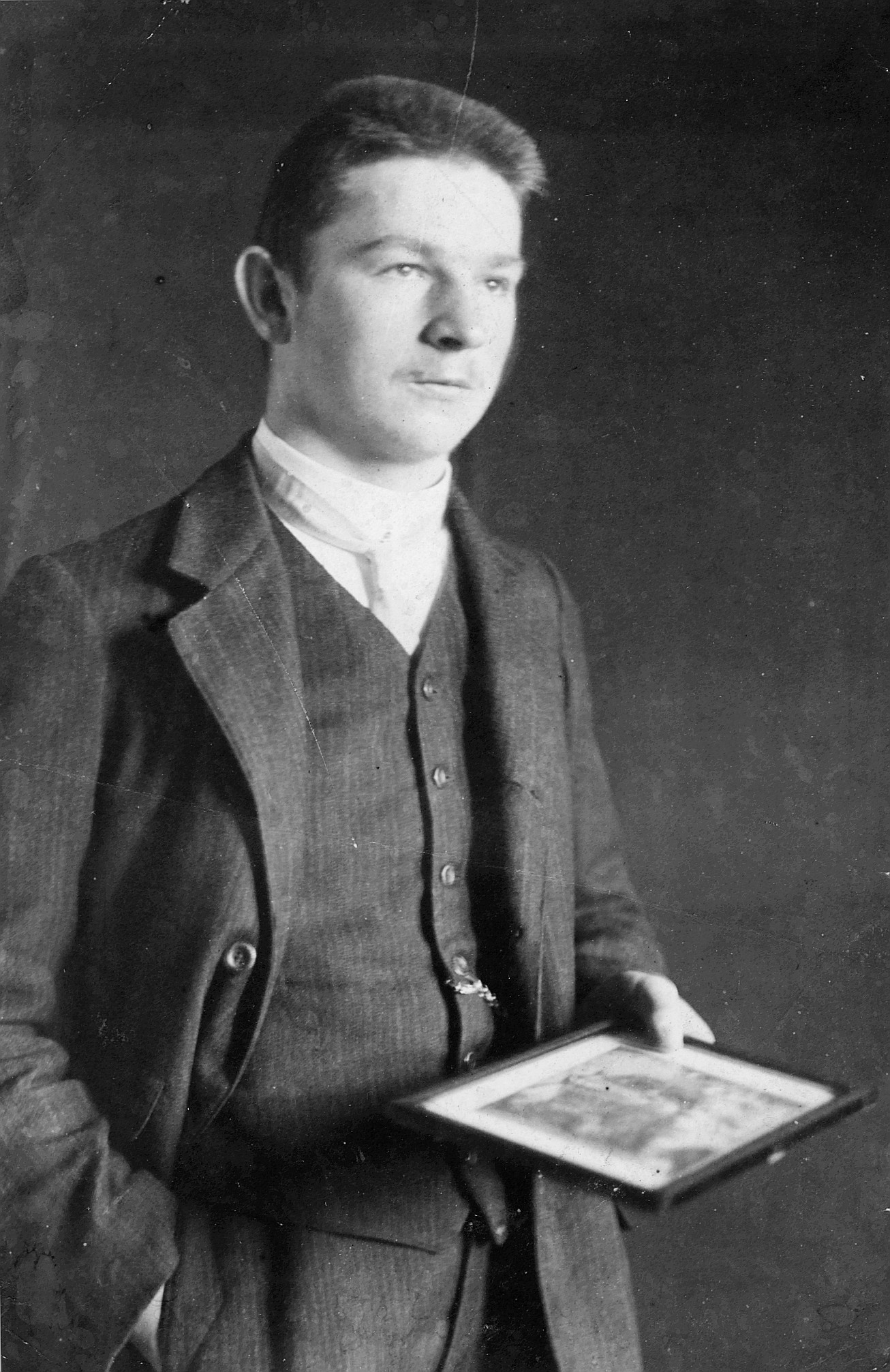 Einzelporträt Robert Hirzel ein gerahmtes Bild in der Hand tragend (1920)